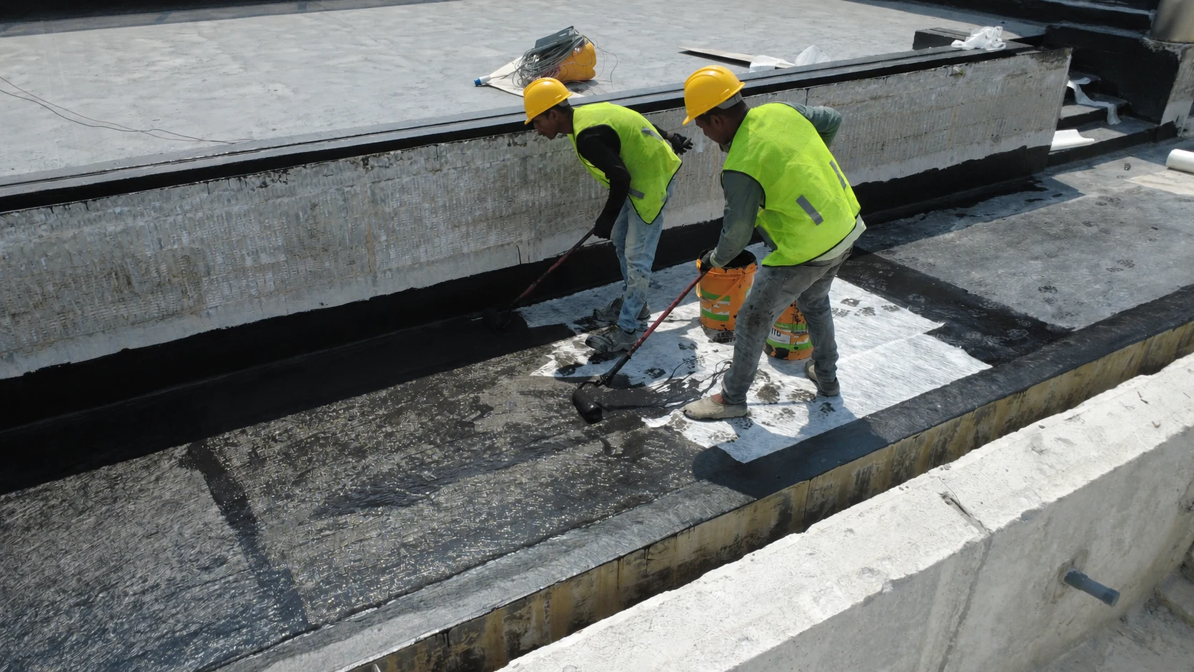 Workers wearing safety helmets during waterproofing installation